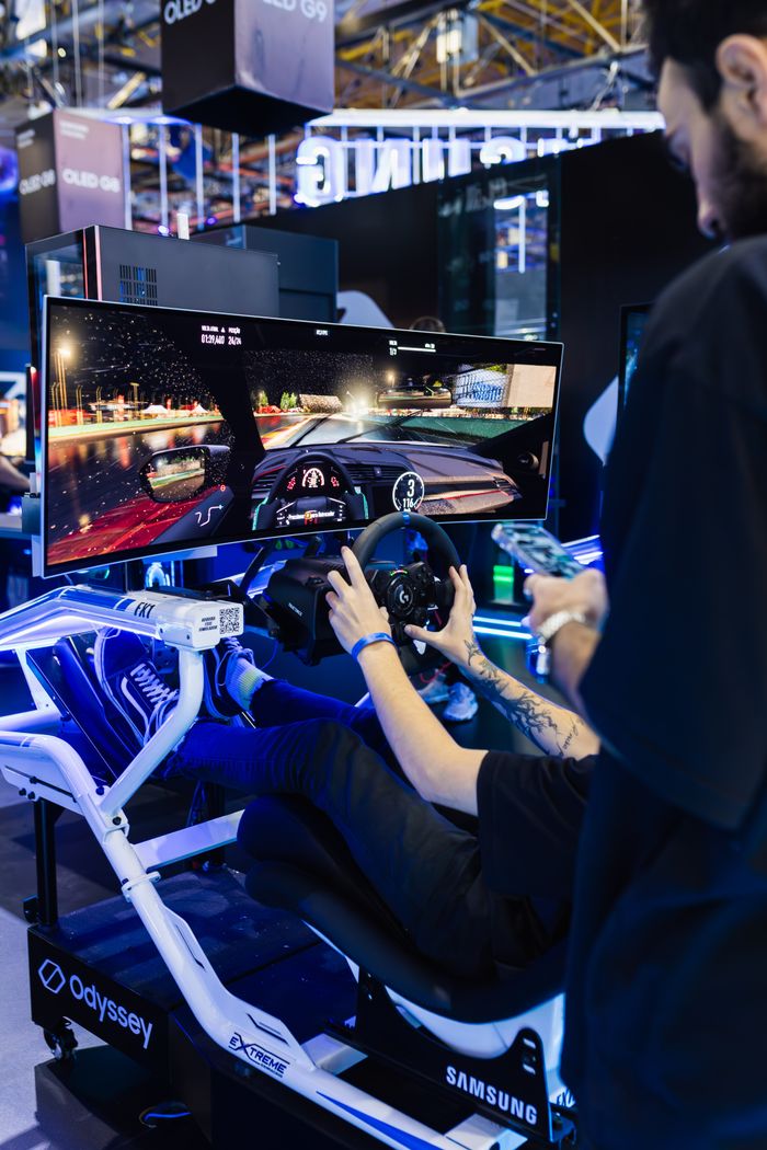 Immersive racing simulator setup with curved monitor at a tech exhibition featuring a dynamic gaming experience.