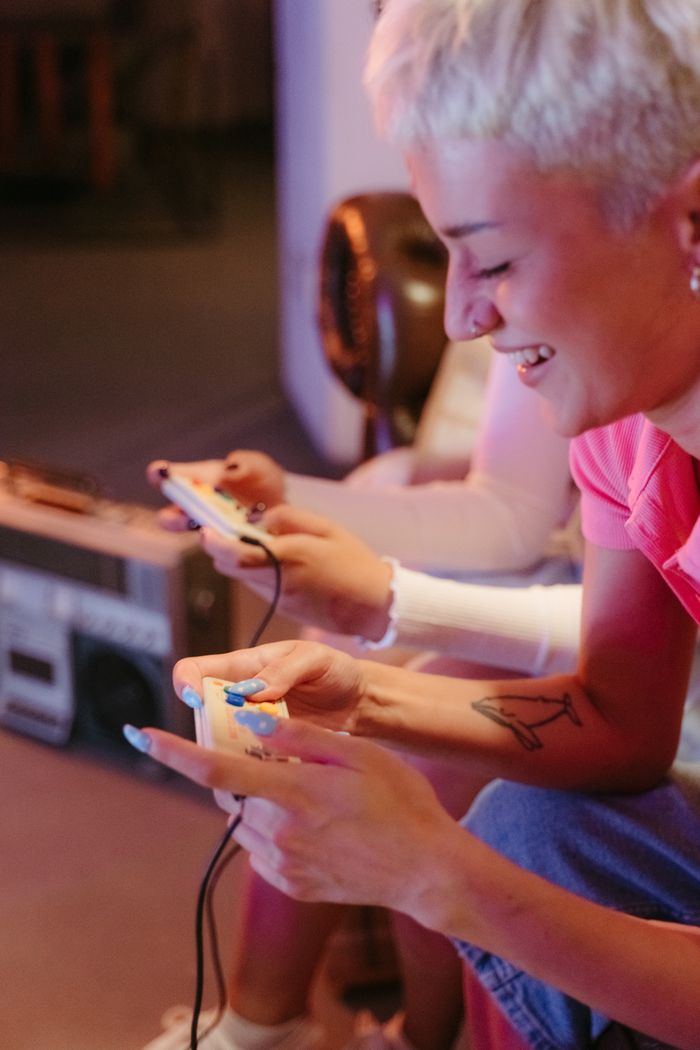 services-03 Laughing woman with short hair and tattoos enjoying a video game session indoors.
