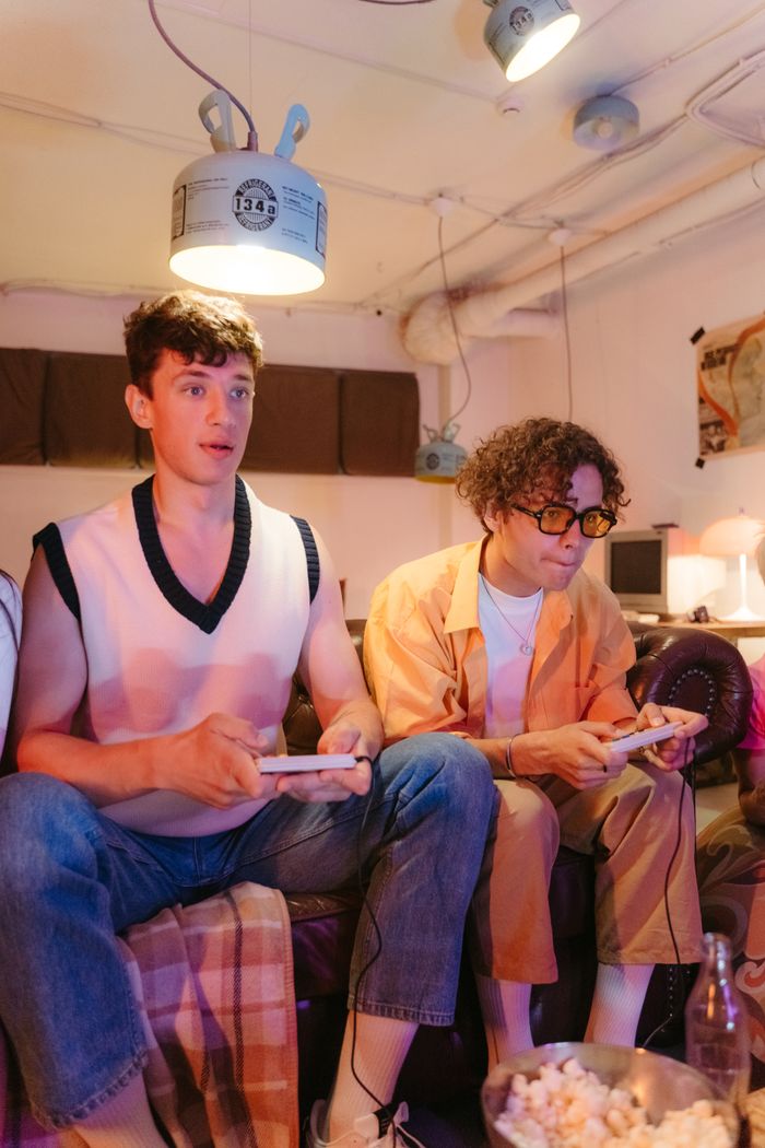 services-04 Two young men intensely playing video games in a cozy, dimly lit basement setting.
